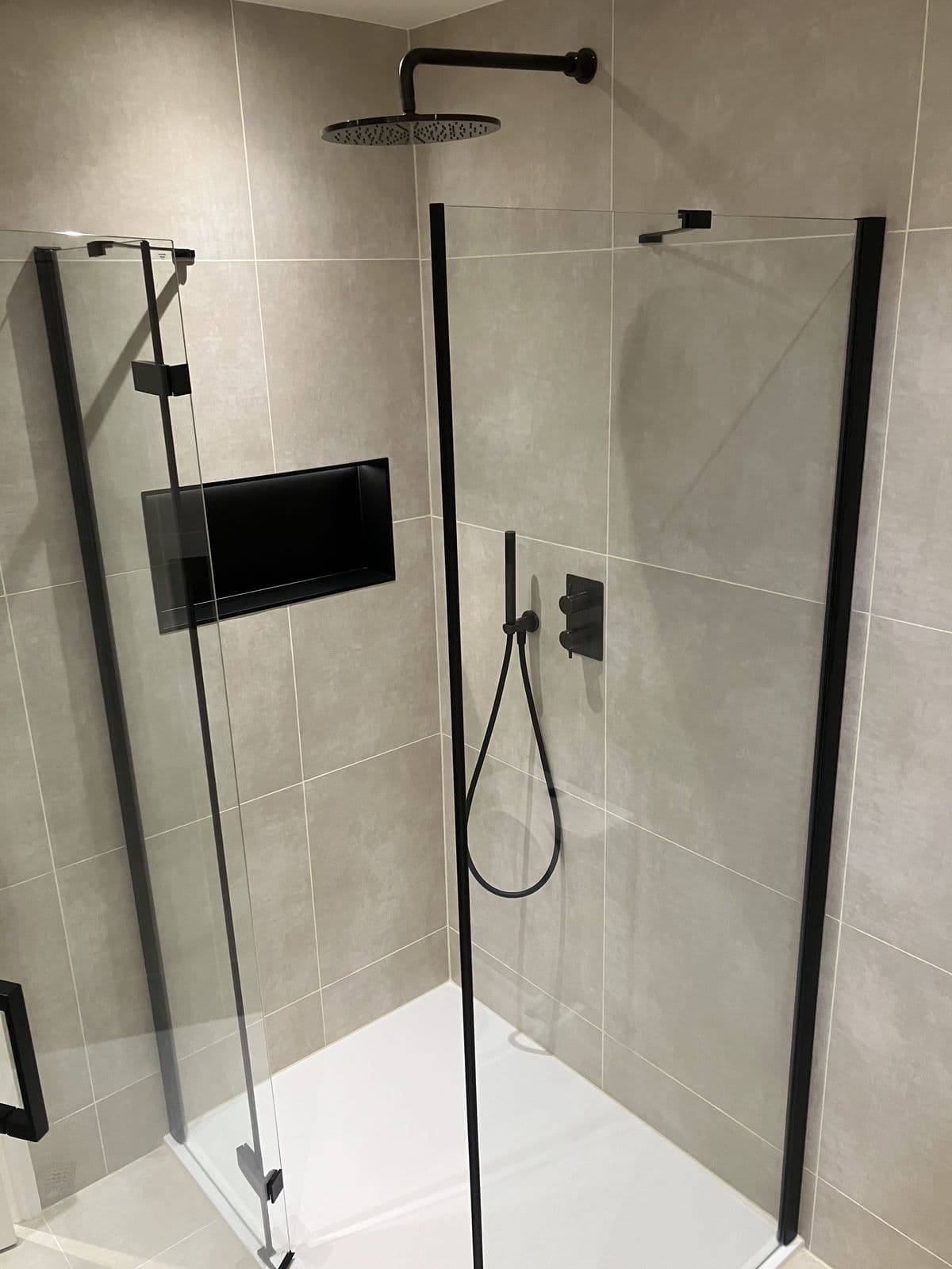Frameless corner shower enclosure with black frame, recessed niche and matt black shower controls