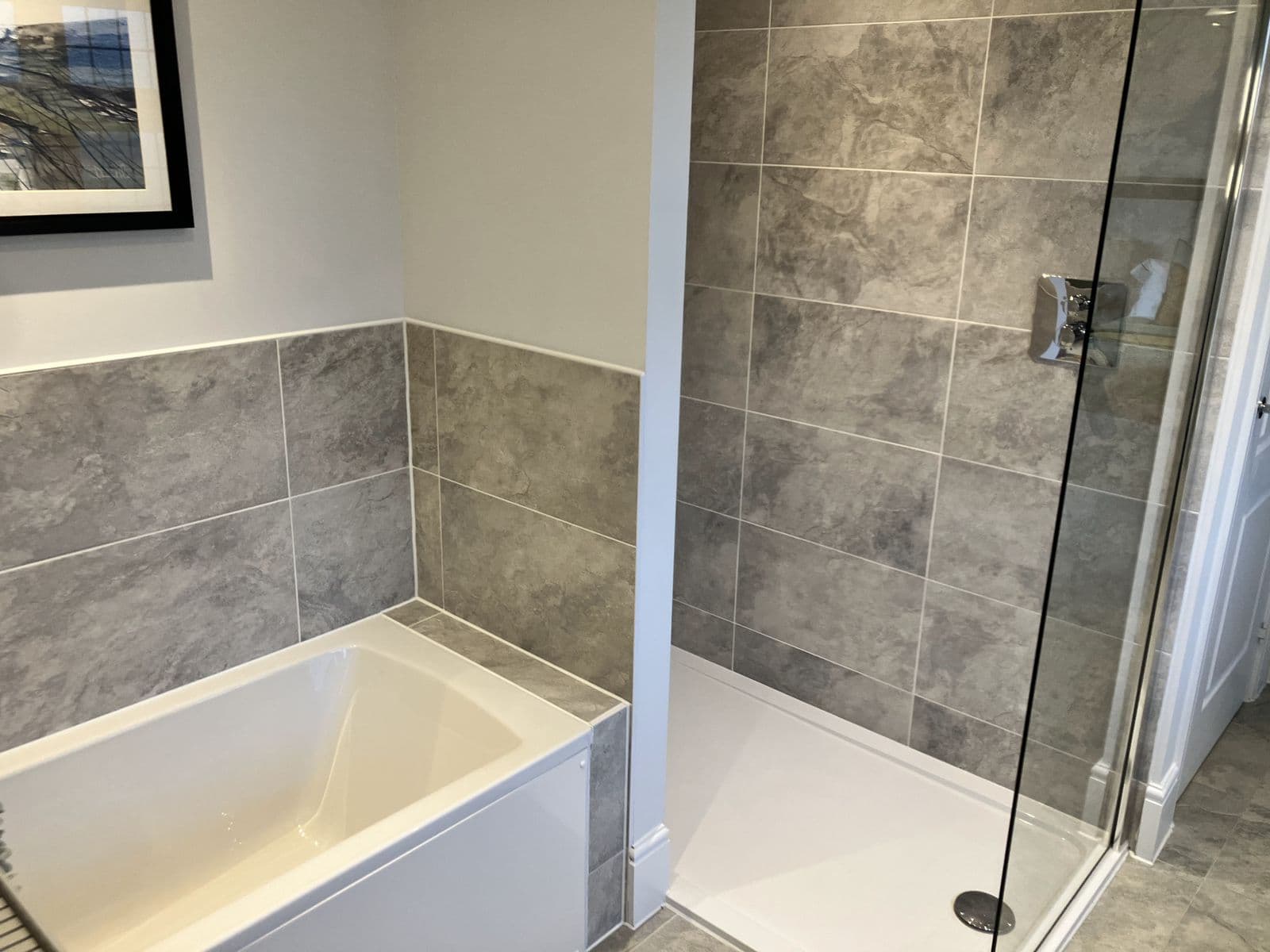 Corner walk-in shower with overhead rainfall head and stone-effect tiling, bedroom visible through the open door beyond