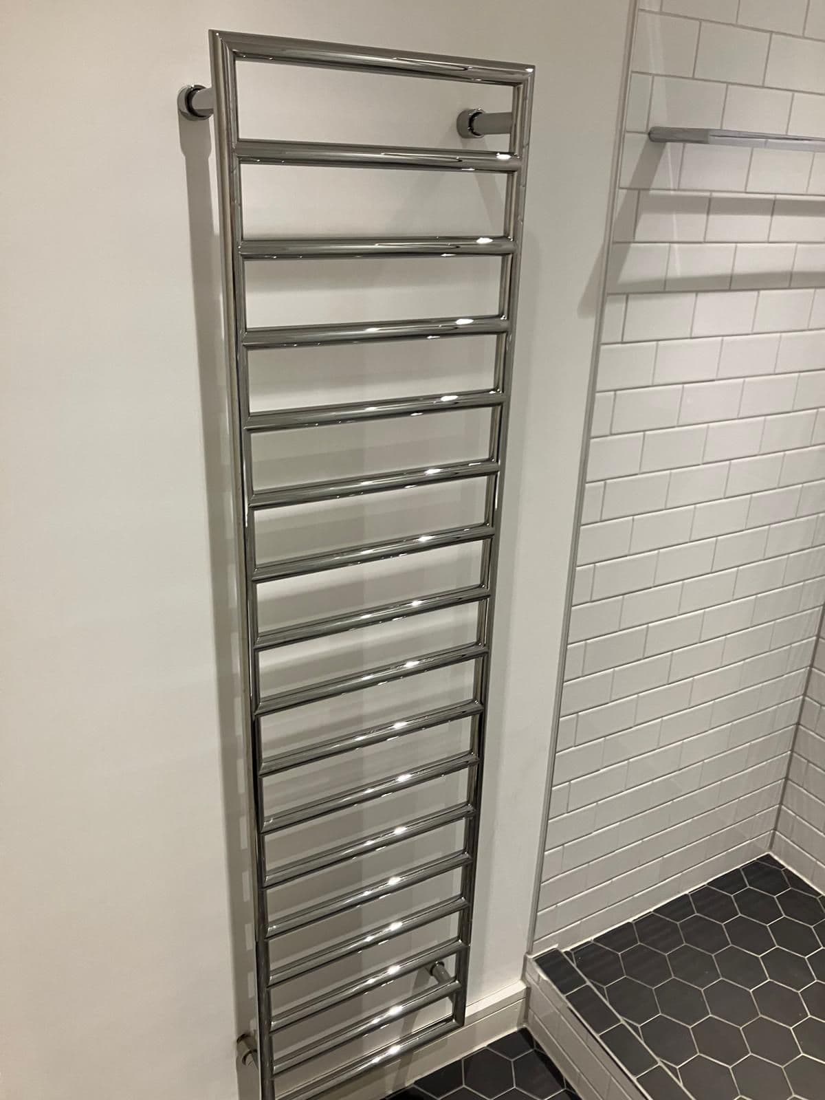 Wall-hung vanity basin and concealed-cistern toilet with metro tiling, marble-effect shelf and chrome heated towel rail
